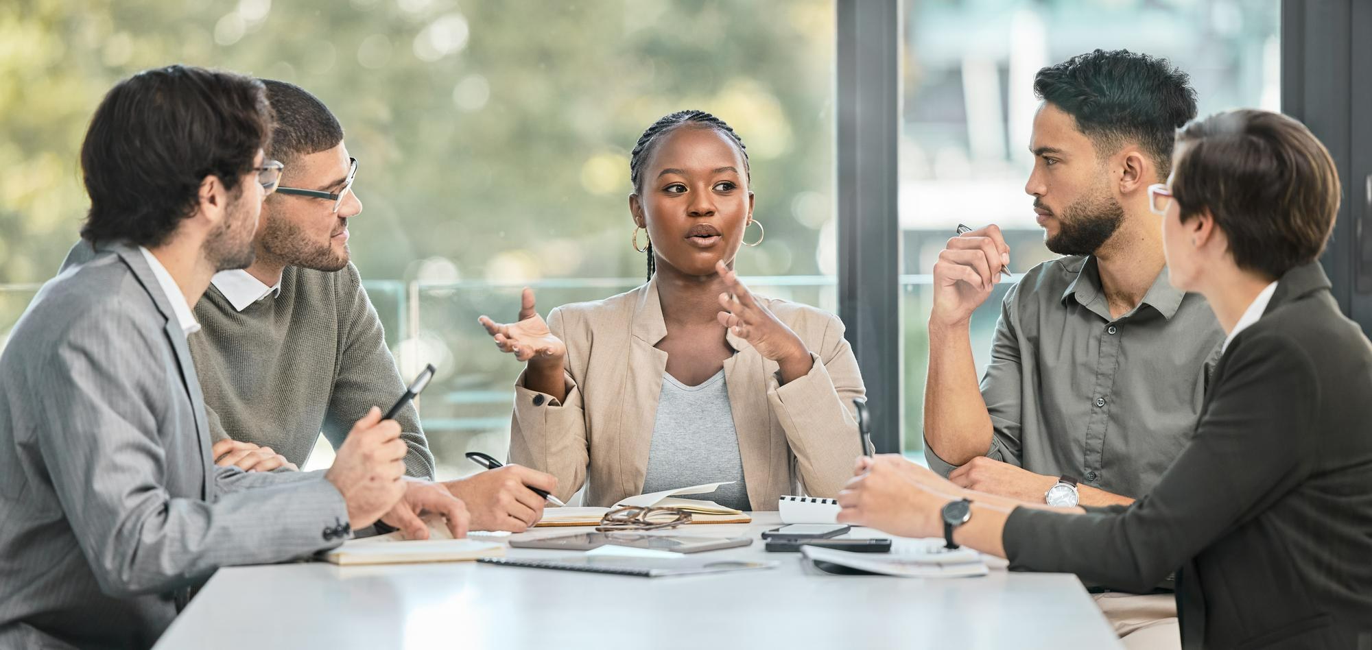 Colleagues in discussion around a table in a bright office