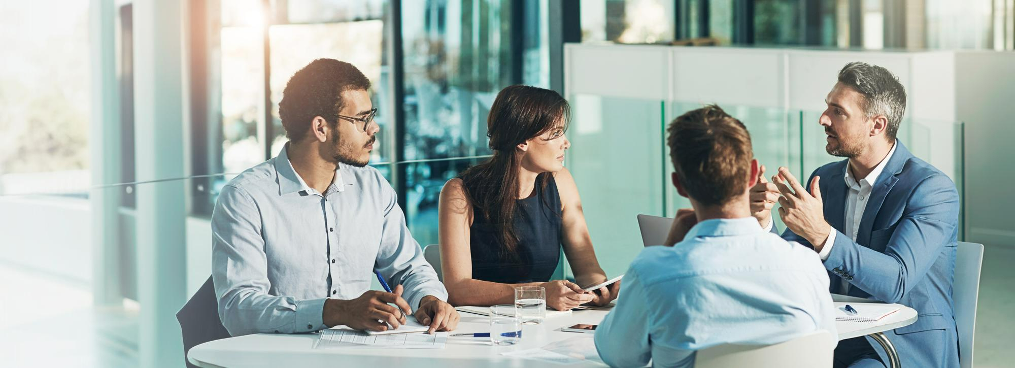 Colleagues in discussion around a laptop in a bright office