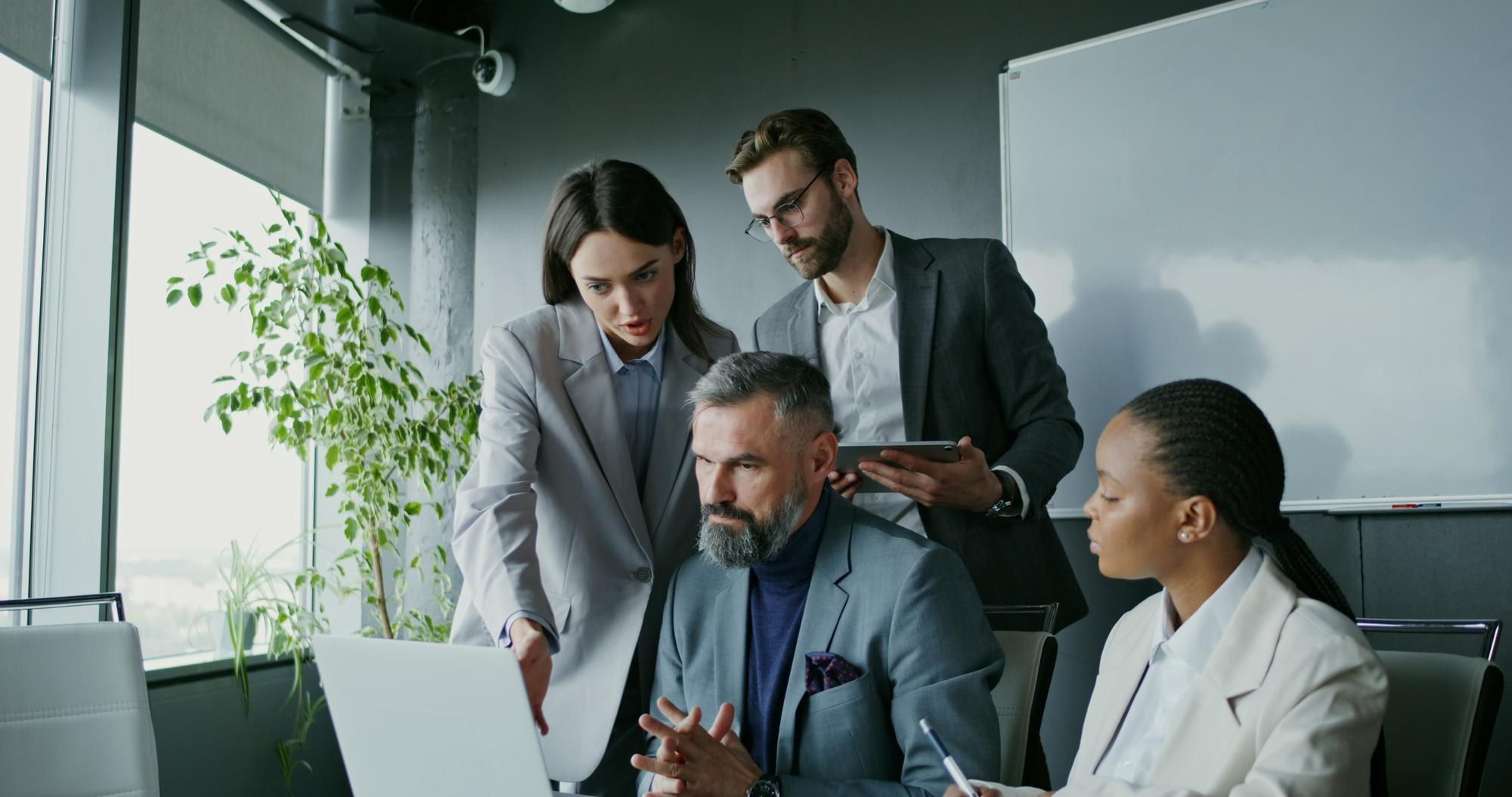 Colleagues reviewing work together around a laptop in a modern office