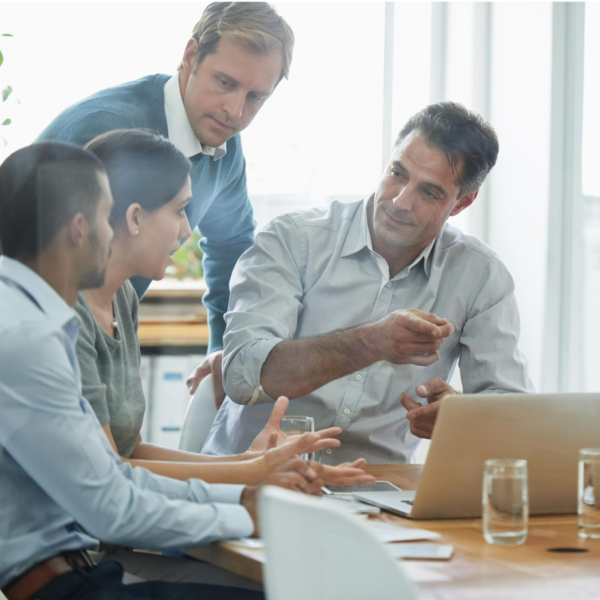 Colleagues reviewing figures together around a laptop